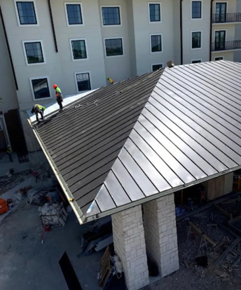 Crew installing standing seam metal roof panels on a commercial project in Iona